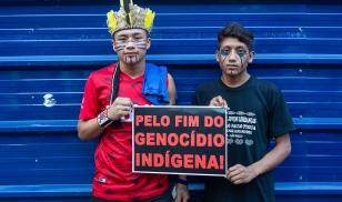 Two young indigenous men protesting holding banner "Stop the indigenous genocide", in march for the rights of the indigenous people. São Paulo, Brazil. 1 January 2019. Editorial Credit: PARALAXIS / Shutterstock.com