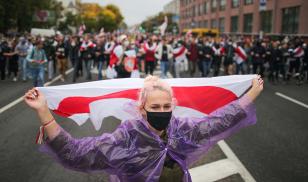 A protester carries a version of the Belarusian flag favored by the democratic opposition during a demonstration in Minsk against the fraudulent August 2020 presidential election. Image credit: Sergei Bobylev\TASS via Getty Images.