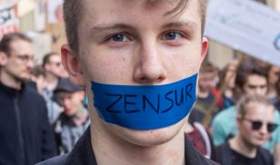 Teenaged man with taped mouth protesting censorship at demonstration against a new copyright law by European Union, "Artikel 13." Erfurt, Germany. 23 March 2019. Editorial credit: Timo Nausch / Shutterstock.com