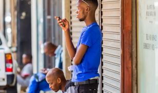 Men using their mobile phones on a sidewalk. Johannesburg, South Africa. Editorial credit: Sunshine Seeds / Shutterstock.com